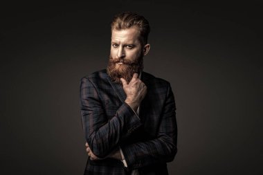 Takım elbiseli şık bir adam. Sakallı bir iş adamı. Gri yolda yabani sakallı adam. Zarif takım elbiseli hırslı bir adam. Erkekler için resmi moda. Erkek giyim modeli. Tasarımcı kıyafeti.