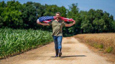 Amerikan bayrağı ve çiftçi adam. ABD bayrağı. Bağımsızlık Günü. Sahadaki adam. Ekin tarlasında Amerikan bayrağı taşıyan adam. Amerika 'nın Bağımsızlık Günü. 4 Temmuz. Amerikan İşçi Bayramı. Ulusal vatanseverlik.