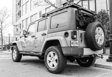 New York, ABD - 31 Mart 2024: 2012 Jeep Wrangler Sınırsız Sahra sarı arabası açık havada park edilmiş, nadir manzara.