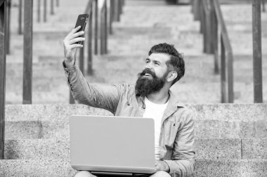 Mutlu adam cep telefonundan selfie çekiyor. Merdivenlerde cep telefonu kamerasına gülümseyen sakallı adam. Mobil internet kullanarak. Mobil iletişim.