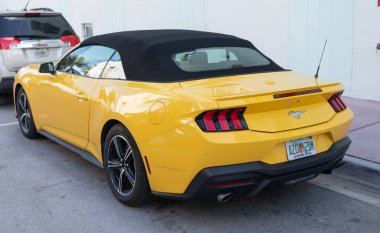 Miami, Florida, ABD - 15 Aralık 2024: Sarı 2024 Ford Mustang EcoBoost üstü açık araba. Ford Mustang 'in lüks arabası. Ford Mustang 'in arabası dışarıda park edilmiş. Ford Mustang sarı renk, köşe görünümü.