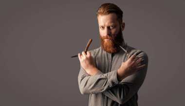 Berber adam makas ve bıçağı kuaförde tut, kopyala uzayda. Berber dükkanı konsepti. Berber adam gri arka planda izole edilmiş. Berber dükkanında elinde makas olan bir adam. Berber dükkanındaki berber..