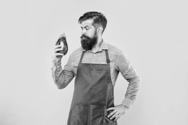 Kırmızı önlüklü, patlıcan sarısı arka plana bakan ciddi bir adam..