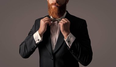 Sakallı, şık görünümlü şık bir adam gri renkli, şık bir papyon stüdyosu ayarlıyor. Smokin tarzı. Resmi biçim.