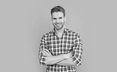 Gri arka planda kareli gömlekli mutlu yakışıklı bir adam. Gündelik tarzda bir adam. Stüdyo fotoğrafı. Beyaz adamın sakalı var..