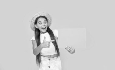 happy teen girl with copy space on green paper on yellow background. pointing finger.