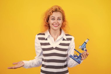 Okul biyoloji öğretmeni kadının elinde mikroskop var. Kadın biyoloji öğretmeni. Okula dönelim. Mikroskobu olan öğretmen sarıda izole edilmiş. Kadınlar için biyoloji bilimi. Mikroskop araştırması. Tıp Bilimi.
