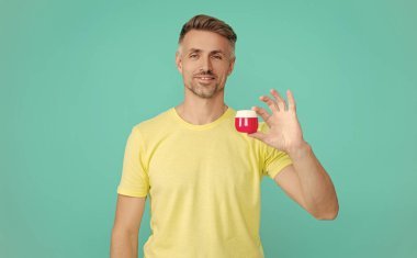 Erkek kozmetik ürünü sunan adam. Mavi renkte yüz kremi gösteren bir adam var. Olgun adam cilt kremi kullanır. Günlük alışkanlık ve kişisel bakım. Cilt güzelliği. Erkek güzellik kozmetiği. Deriyi temizle..
