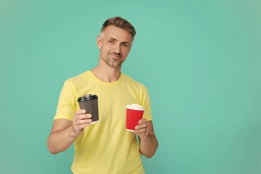 Yaşam tarzı konsepti. Kafeinsiz içiyorum. Çay içen adam. Sıcak bir sabah, rahatla. Kahveci adamla kahve molası. Olgun bir adam mavi üzerine kafeinsiz kahve fincanı seçer. Sabah kahvesi vakti. Pankart.