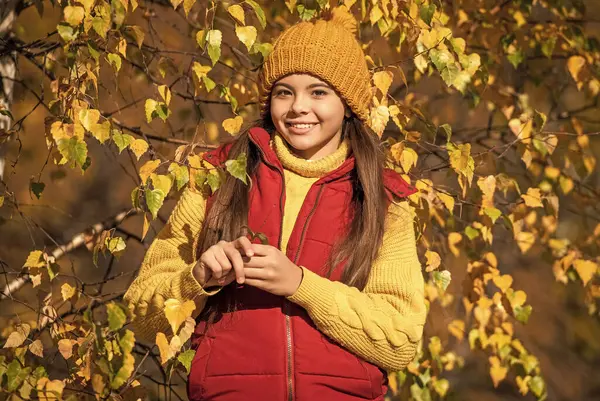 Okul zamanı güz yapraklarıyla dışarıda gezen neşeli genç çocuk..