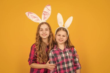 Sarı arka planda tavşan kulaklı neşeli Paskalya çocukları.