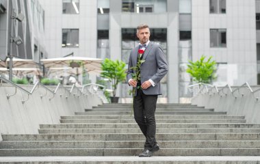 elegant man in tux. man wearing tux bowtie outdoor. handsome tux man with red rose. copy space.