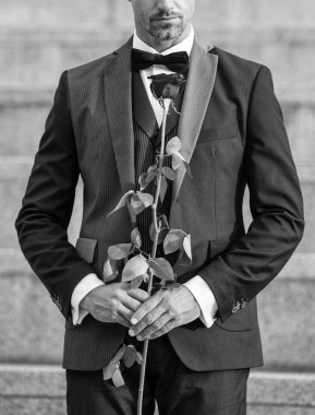 love rendezvous concept. cropped view of tux man with love rose. flower gift for love day.