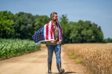 4 Temmuz. İşçi bayramı. Amerikan bayrağı ve çiftçi adam, hasat zamanı. ABD bayrağı. Bağımsızlık Günü. Sahadaki adam. Sahada Amerikan bayrağı taşıyan vatansever adam. Amerika 'nın Bağımsızlık Günü. Mutlu ve özgür.