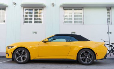 Miami, Florida, ABD - 15 Aralık 2024: Sarı 2024 Ford Mustang EcoBoost üstü açık araba. Ford Mustang 'in lüks arabası. Ford Mustang 'in arabası dışarıda park edilmiş. Ford Mustang sarı renk, köşe görünümü.