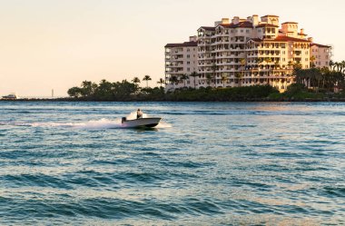 Marinaya yüzen bir tekne. Fisher Adası 'nda lüks bir yat teknesi. Yaz tatili. Fisher Adası konut binası ve lüks yat teknesi. Miami 'de Fisher Adası' na yat gezisi..