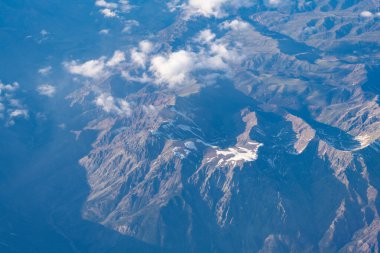 Dağlı, bulutlu bir manzara. Bulut ve dağ zirvesi hava manzarası. Dağ manzarasının havadan görünüşü. Hava bulutlu görünüyor. Uçaktan manzara. Dağların tepesinde, bulutların içinde. Manzara Görünümü.