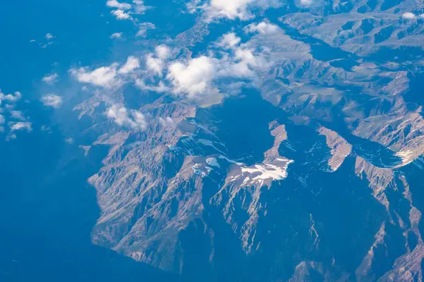Dağlı, bulutlu bir manzara. Bulut ve dağ zirvesi hava manzarası. Dağ manzarasının havadan görünüşü. Hava bulutlu görünüyor. Uçaktan manzara. Dağların tepesinde, bulutların içinde. Manzara Görünümü.