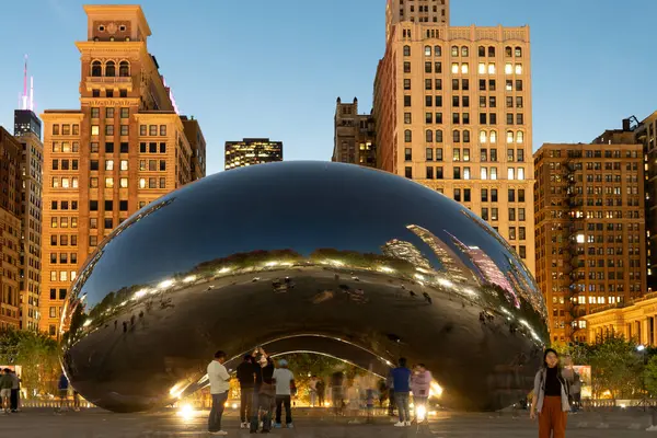 Chicago, Illinois, ABD - 22 Ekim 2024: Millennium Park ve ünlü Cloud Gate heykeli. Fasulye heykeli. Gökdelenli gece şehri manzarası. Chicago Milenyum Şehir Parkı. Bulut Kapısı.