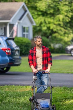 Çim biçme makinesi yeşil çim biçer. Bahçıvan adam çim biçiyor. Bahçe bakımı. Elektrikli çim biçme makinesi. Peyzaj tasarımı. Çim biçme makinesi. Arka bahçe çim bakımı. İspanyol bahçıvan. Kenarları biçme makinesiyle buduyor.