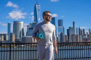 Spor aktivitesi. Yoga koçu. Sporcu adam antrenmana hazır. Sağlıklı bir yaşam tarzı. Spor ve spor. Eğitim için yoga minderi. New York 'ta sporcu. Manhattan 'da spor kıyafetli bir adam..