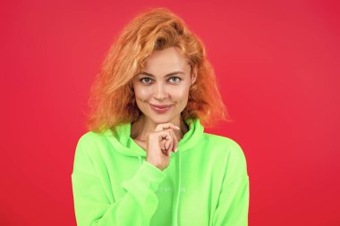 Havalı flörtçü kadın ya da kızıl saçlı manken gündelik tarz ve moda kapüşonlu parlak renkli pembe üzerine izole edilmiş..