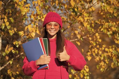 Eylül 'deki bilgi günü. Sonbahar eylül ayındayız. Eylül 'ün 1' inde okul ödevi olan genç bir kız. Genç kız açık havada düşmeyi sever. Okula dönüyorum. Genç kızların okul eğitimi. başparmak yukarı.