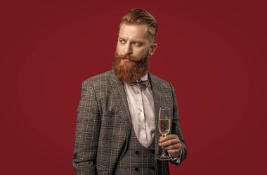 Başarıyı kutluyoruz. - Şerefe. Resmi görünüşlü sakallı adam. Şampanyayla kutlayın. Kutlama ve tezahürat. Şık smokinli adam kırmızı üzerine izole edilmiş şampanya bardağı tutuyor..