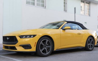 Miami, Florida, ABD - 15 Aralık 2024: Sarı 2024 Ford Mustang EcoBoost üstü açık araba. Ford Mustang 'in lüks arabası. Ford Mustang 'in arabası dışarıda park edilmiş. Ford Mustang sarı renk, köşe görünümü.