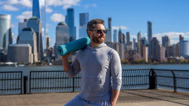 Eğitim için yoga minderi. New York 'ta sporcu. Manhattan 'da spor kıyafetli bir adam. Sağlık ve etkinlik, yoga koçu. Sporcu adam antrenmana hazır. Sağlıklı bir yaşam tarzı. Spor ve spor.