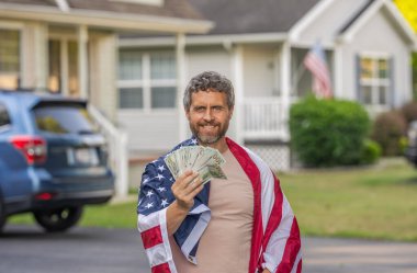 Amerikan bayrağı ve dolar parası olan adam. Enflasyon konsepti. Amerikan vergi politikası. İspanyol adam ve Amerikan bayrağı. Amerika 'da vergi ödemek. Katma değer vergisi. Vergi sistemi. ABD 'li vatandaşın geliri.