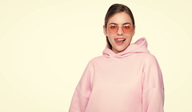 Sıradan pembe kapüşonlu, gözlüklü, dudaklarını yalayan, beyaz tenli mutlu genç kadın..