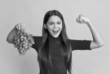 Başarılı çocuk sarı arka planda taze üzüm tutar..