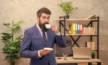 Ofiste fotokopi alanı olan kahve içen sakallı bir iş adamı..