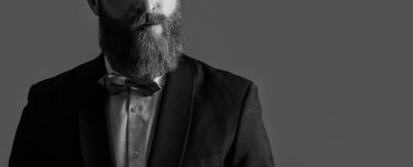 Stüdyo, smokin giysisinin manzarasını kesmiş. Smokin giyen adam. Smokin resmi kıyafet. Smokinli sakallı adam gri arka planda izole edilmiş..