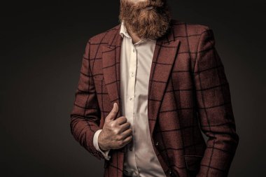 Zarif takım elbiseli hırslı bir adam. Erkekler için resmi moda. Erkek giyim modeli. Takım elbiseli şık bir adam. Sakallı bir iş adamı. Gri yolda yabani sakallı adam. Kırpılmış görünüm.