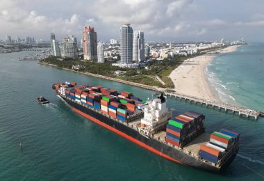 Miami Limanı. Miami 'de konteynırlı kargo gemisi, hava manzaralı. Kargo gemisinde nakliye konteynırı. Kargo gemisi limandan ayrılıyor. Konteyner gemisi. İhraç ve ithalat. Kargo işi. Miami plajı.