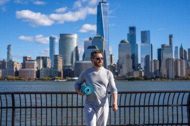 Sporcu adam antrenmana hazır. Sağlıklı bir yaşam tarzı. Spor ve spor. Eğitim için yoga minderi. New York 'ta sporcu. Manhattan 'da spor kıyafetli bir adam. Yoga koçu. Atletik egzersiz.