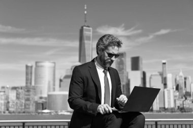 New York 'ta serbest çalışan bir iş adamı. İnternette çalışan bir iş adamı. İş adamı dışarıda dizüstü bilgisayarla çalışıyor. Adam internet tarayıcısından iş e-postası ve sörf yolluyor. Dijital veri yönetimi. İletişim.