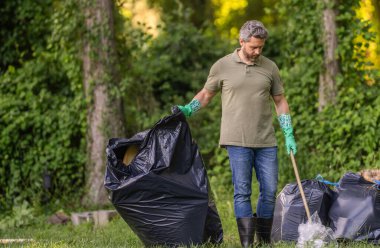 Çevresel koruma. Çevreci adam. Çevresel koruma. Çevreyi koru. Çevre plastik kirliliği. Gönüllü adam ormanda çöp topluyor. Çöp toplama günü.