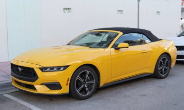 Miami, Florida, ABD - 15 Aralık 2024: Sarı 2024 Ford Mustang EcoBoost üstü açık araba. Ford Mustang 'in lüks arabası. Ford Mustang 'in arabası dışarıda park edilmiş. Ford Mustang sarı renk, köşe görünümü.