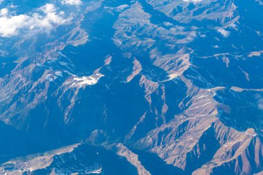Uçaktan manzara. Dağların tepesinde, bulutların içinde. Dağlı, bulutlu bir manzara. Bulut ve dağ zirvesi hava manzarası. Dağ manzarasının havadan görünüşü. Hava bulutlu görünüyor. Macera.