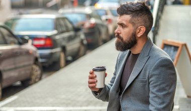 İş hayatı, mola zamanı. Sabah kahvesi içen adam. Kahve molası. Günlük stil rutini. Sakallı adam şehir caddesinde kahve içiyor. Sokakta elinde kahve tutan düşünceli bir adam..