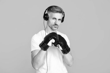 Kulaklık takan olgun bir boksör. Sporcu boks. Güçlü adam müzik dinler. Spor salonundaki sporcu. Spor giyim bölümünde boksör. Egzersiz ve yumruk. Boks eldivenli sporcu mavi üzerine izole edilmiş. Başarı.