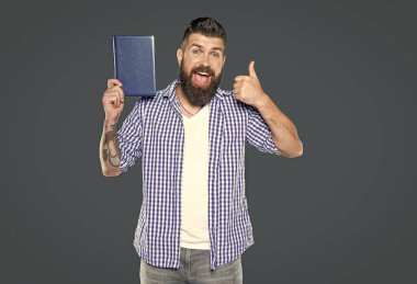 Şaşırmış bir adam gri arka plan hakkında kitap tavsiye ediyor. başparmak yukarı.