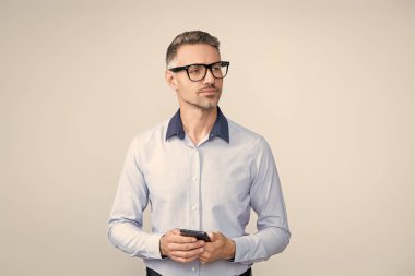 Telefonu olan olgun bir iş adamı. Telefon kullanan bir iş adamı. Gri yolda insan telefonu görüşmesi izole edildi. İş adamı sohbeti. İş adamı mesajlaşması ve mesajı. Sosyal ağ. Gerçek zamanlı iletişim.