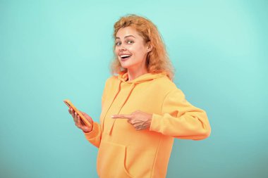 Milenyum kadını internette sohbet ediyor. İş sohbeti iletişimi. İnternetten alışveriş. Kadın telefonu kullanıyor. Blogda sohbet eden kız. Alışverişte telefon kullanmak. İnternette çalışan bir kadın. İşaret parmağı.