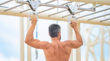 Sporcu adam egzersiz yapıyor. Adam kaslı sırt sporcusu açık hava spor salonunda barfiks çekiyor. Spor yaşam tarzı. Kas kasları ve trisepsler. Güçlü bir atlet. Adam yanaşıyor. Spor eğitimi..