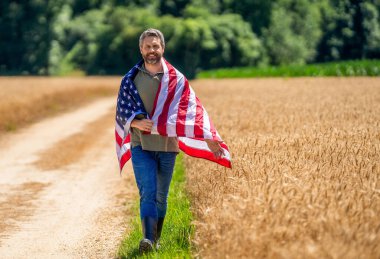 Sahadaki adam. Ekin tarlasında Amerikan bayrağı taşıyan adam. Amerika 'nın Bağımsızlık Günü. 4 Temmuz. Amerikan İşçi Bayramı. Amerikan bayrağı ve çiftçi adam. ABD bayrağı. Bağımsızlık Günü. Pankart reklamı.