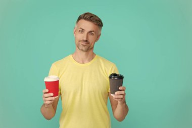 Olgun bir adam mavi üzerine kafeinsiz kahve fincanı seçer. Sabah kahvesi vakti. Yaşam tarzı konsepti. Kafeinsiz içiyorum. Çay içen adam. Sıcak bir sabah, rahatla. Kahveci adamla kahve molası. Reklam..